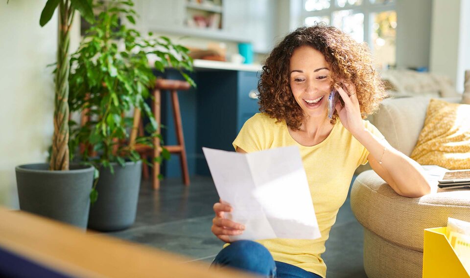 Frau, mit Brief in der Hand, telefoniert mit dem Handy