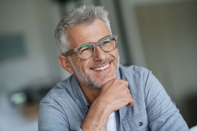  Lächelnder Mann mit Brille blickt freundlich in die Kamera.