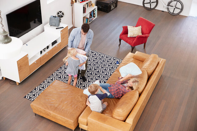 Eine Familie spielt zusammen in einem gemütlichen Wohnzimmer mit einer Leder-Couch und genießt die gemeinsame Zeit.
