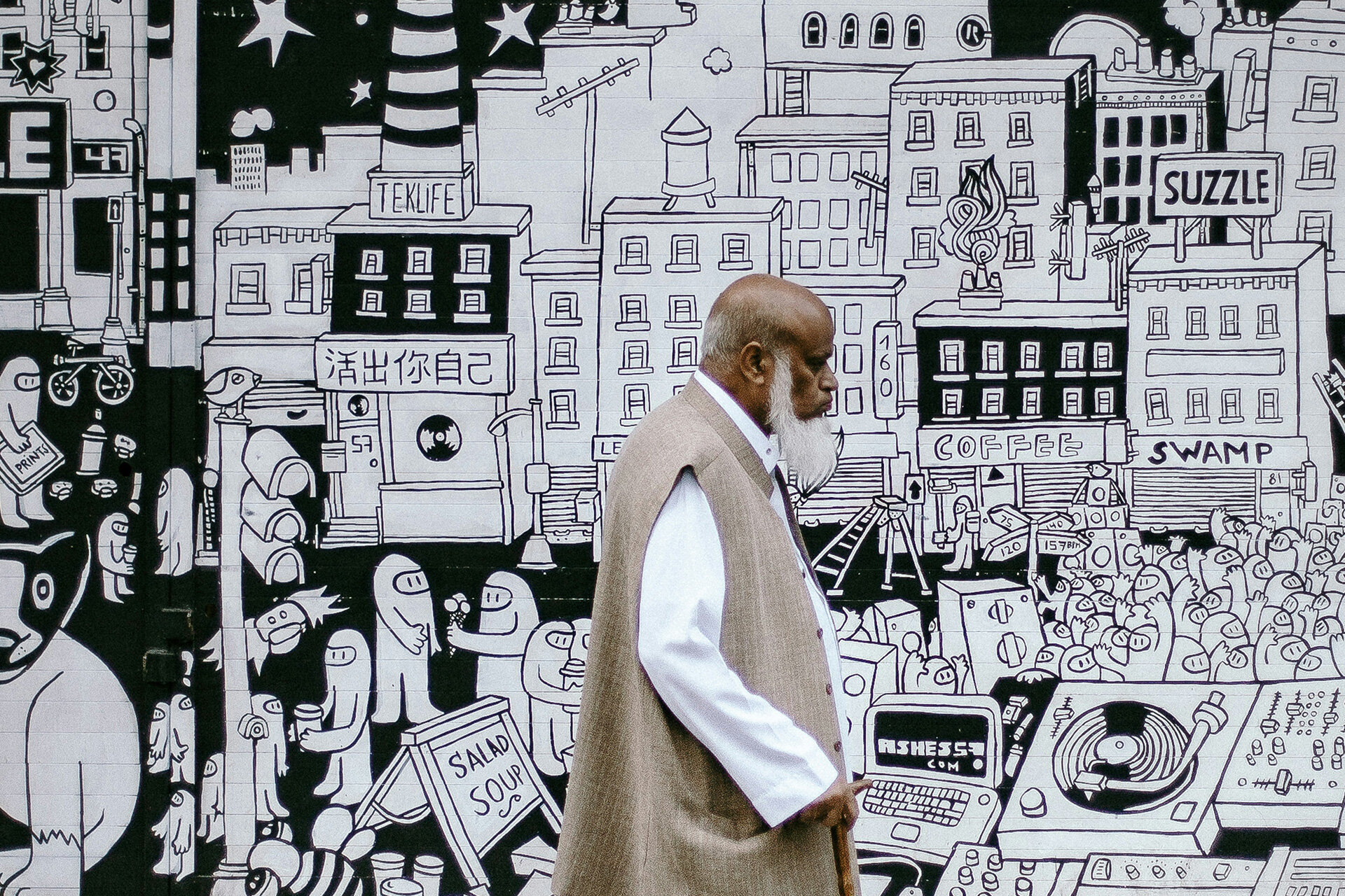 Automatische Anmeldung bei Betriebsrenten in der EU | © Clem Onojeghuo / Unsplash the picture shows an older gentleman in front of a wall with black and white doodles about future topics | © Clem Onojeghuo / Unsplash