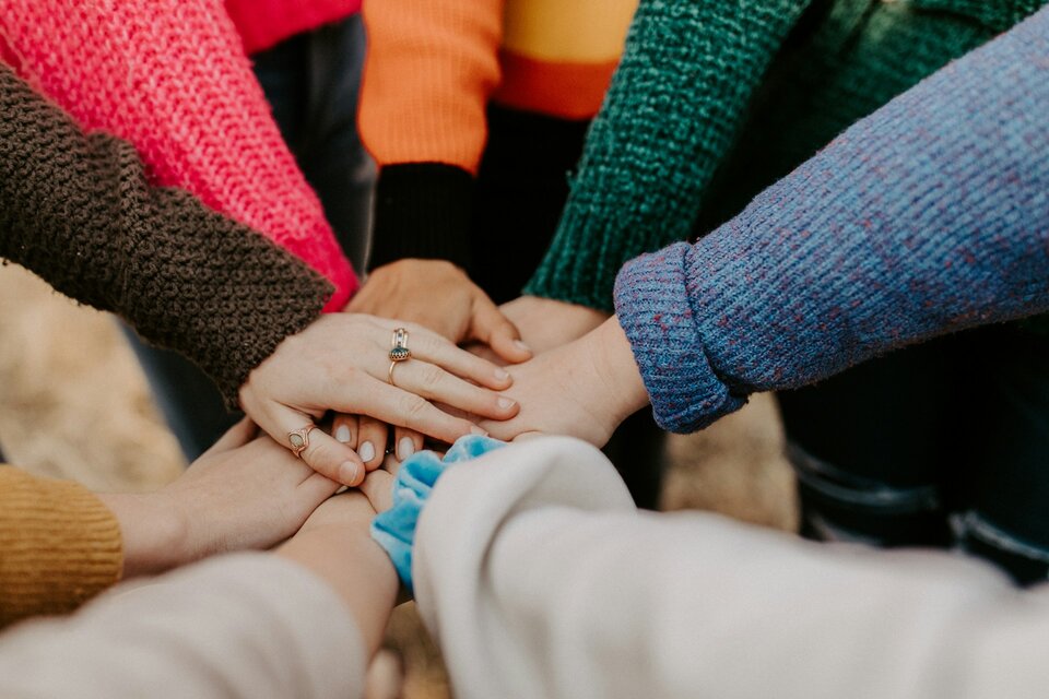 Versicherungsschutz für Ehrenamtliche: Haftung und Absicherung | © Hannah Busing / Unsplash Auf dem Bild sieht man die Hände mehrerer Menschen, die sie übereinander legen als Zeichen der Gemeinschaft | © Hannah Busing / Unsplash