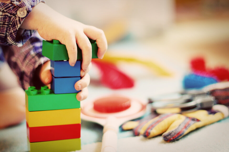 Kinder gut betreut und versichert: Was Familien wissen sollten | © FeeLoona / Pixabay Auf dem Bild sieht man ein Kind, das gerade mit farbigen Plastikbauklötzen einen Turm baut. | © FeeLoona / Pixabay