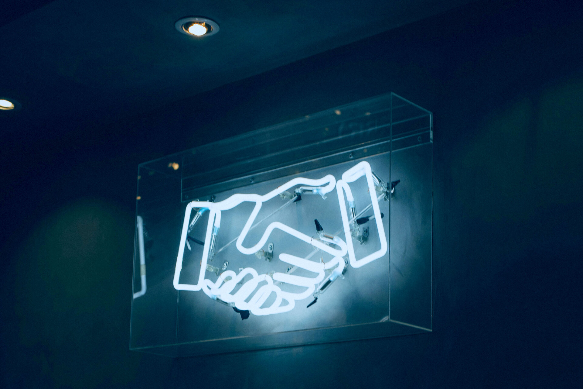 Enhancing Transparency and Consumer Protection in Pension Sector | © charlesdeluvio / Unsplash Auf dem Bild sieht man Neonröhren in der Form von einem Handschlag | © charlesdeluvio / Unsplash