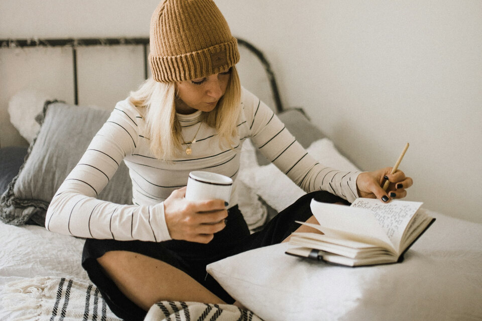 Versicherungen für Auszubildende und Studienanfänger | © Kinga Howard / Unsplash Das Bild zeigt eine junge Dame mit ihrem Planer und einer Tasse Tee in der Hand auf ihrem Bett | © Kinga Howard / Unsplash
