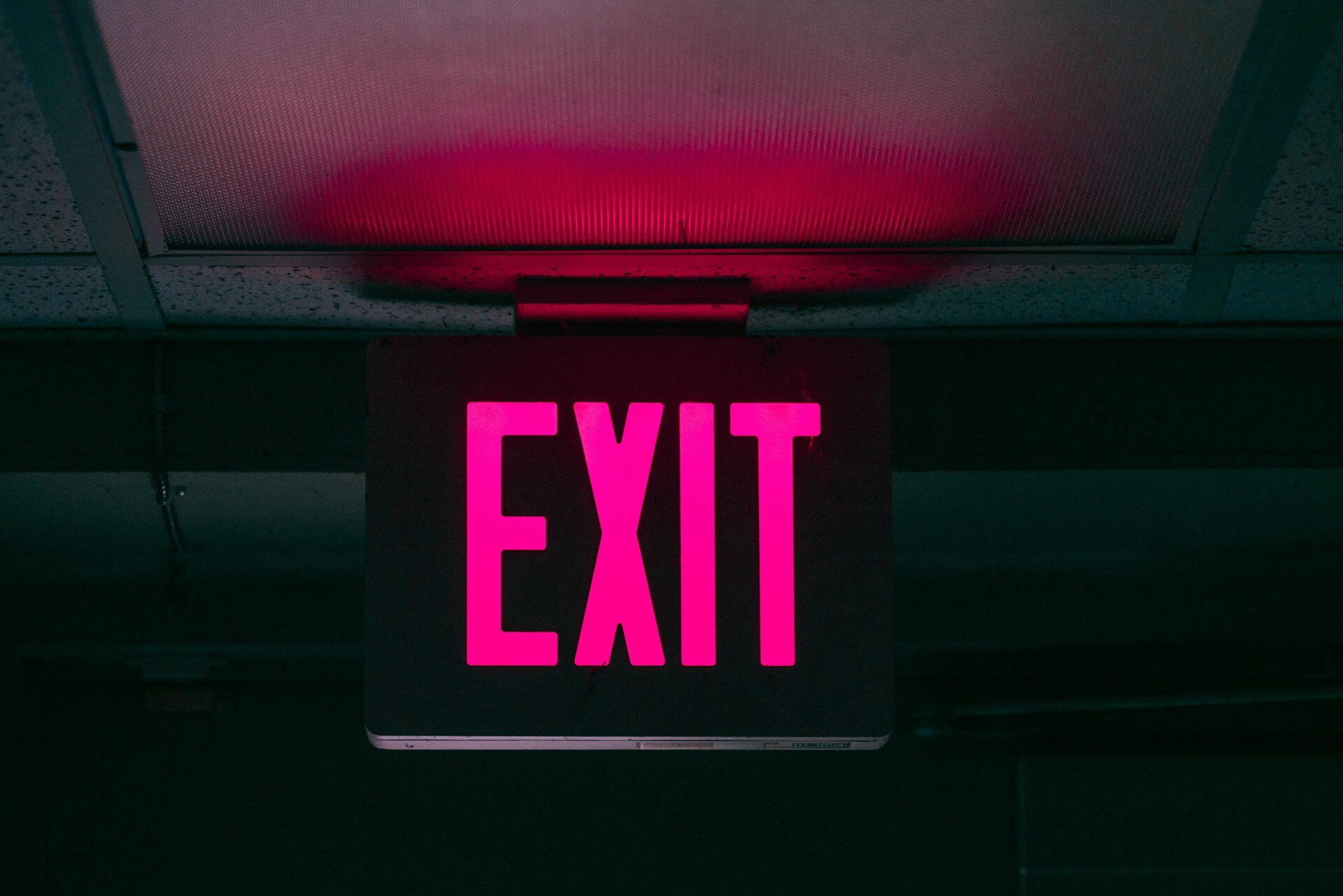 Wie kündige ich einen Versicherungsvertrag | © Keagan Henman/ Unsplash Das Bild zeigt ein pinkes Exit-Schild in einer Unterführung | © Keagan Henman/ Unsplash