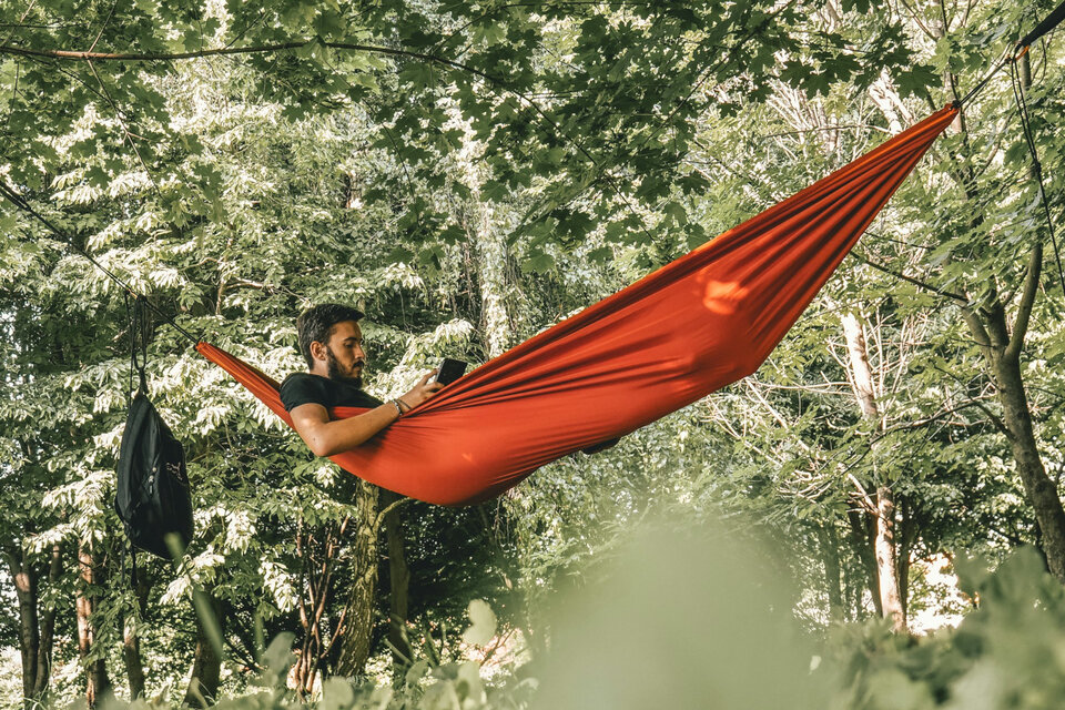 Nachteile von Embedded Insurance: Bequemlichkeit kann teuer werden | © Kornél Máhl / Unsplash Das Bild zeigt einen Mann in einer roten Hängematte. | © Kornél Máhl / Unsplash
