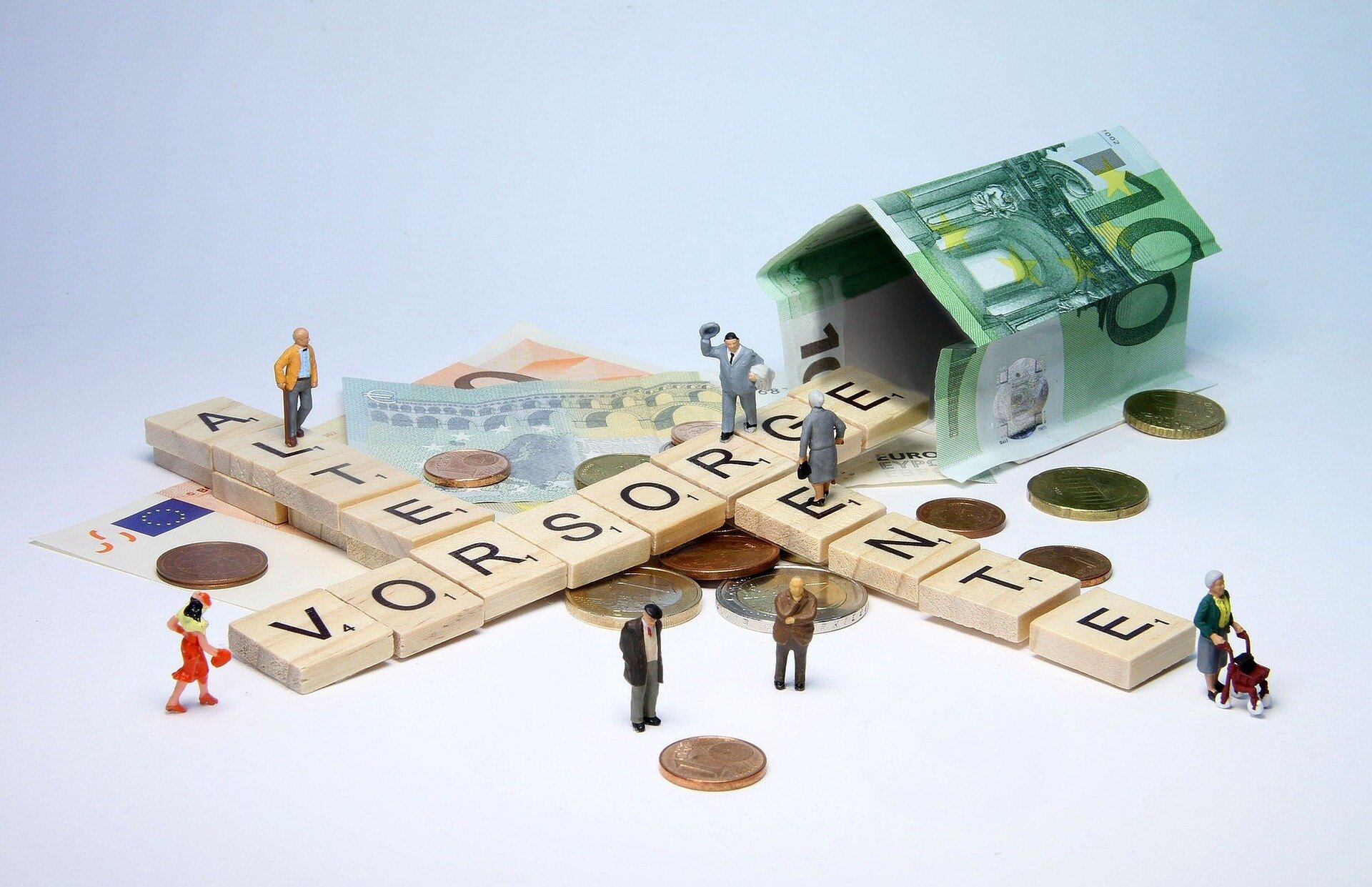 Altersvorsorge vs. Altersversorgung: Worin liegt der Unterschied? | © wir_sind_klein / pixabay Auf dem Bild sieht man mit Scrabble-Holzsteinen die Worte Alter, Vorsorge und Rente, kleine Figuren und ein aus einem Hundert-Euro-Schein gefaltetem Häuschen | © wir_sind_klein / pixabay