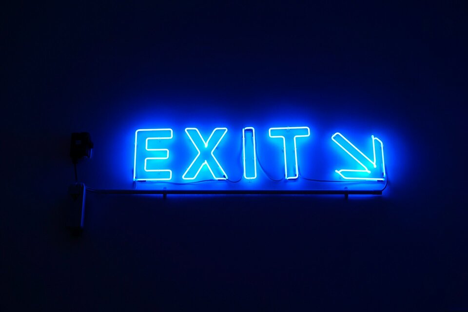 Allianz-Chef Bäte über Run-Off-Optionen bei Allianz Leben | © Dustin Tramel / Unsplash Das Bild zeigt blaue Leuchtbuchstaben, die EXIT und einen Pfeil schräg nach rechts unten zeigen | © Dustin Tramel / Unsplash