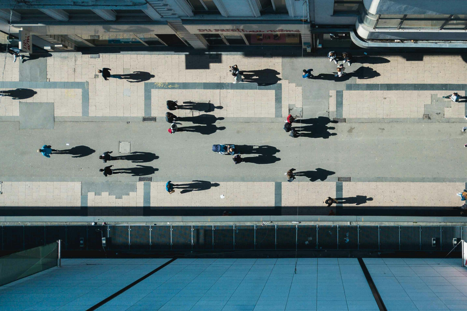 Blick aus der Vorgelperspektive: Mehrere Personen spazieren auf einer Straße in der Stadt. | © Aurelien Romain / Unsplash