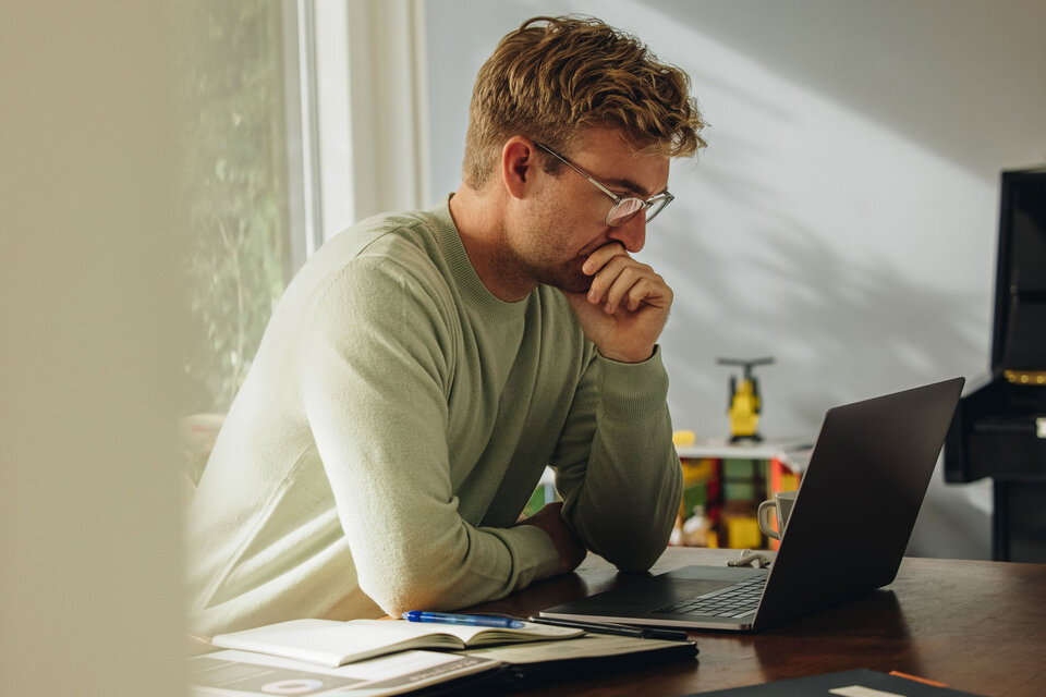 Mann mit Brille sitzt vor einem Laptop