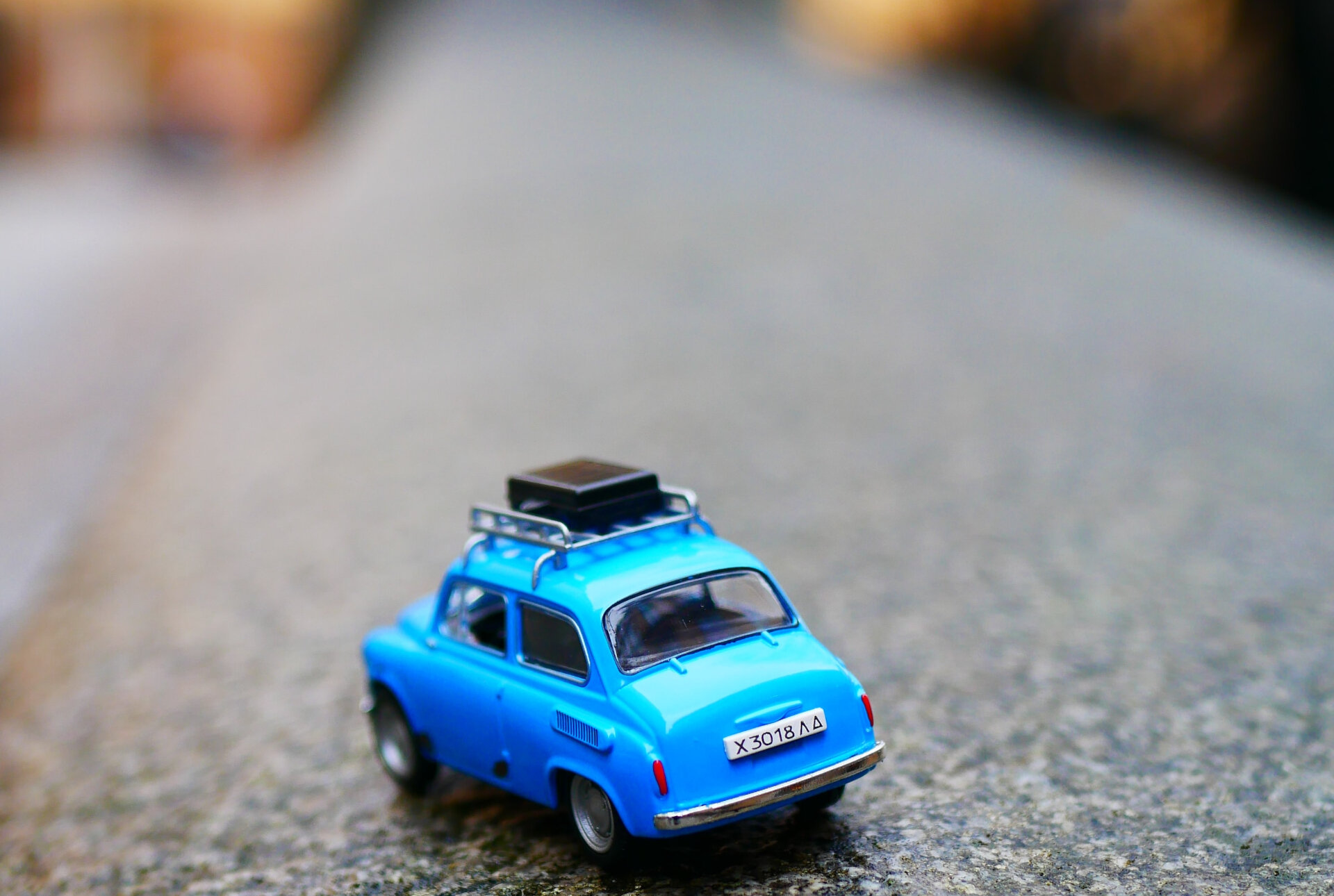 Sicher reisen mit Dachbox & Versicherungsschutz | © Karine germain / Unsplash Das Bild zeigt ein kleines blaues Spielzeugauto mit einem Koffer auf dem Dachgepäckträger | © Karine germain / Unsplash