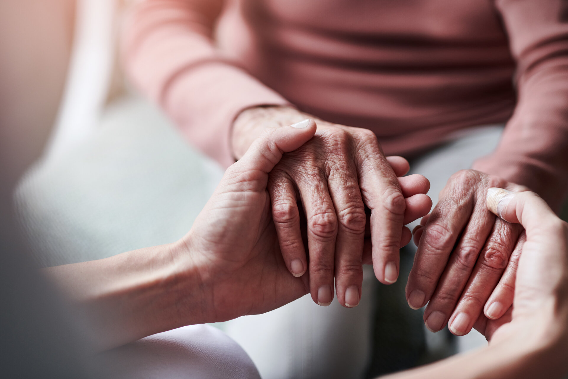 Zwei Hände umschließen die Hände einer älteren Dame. | © Cecilie Arcurs / iStock