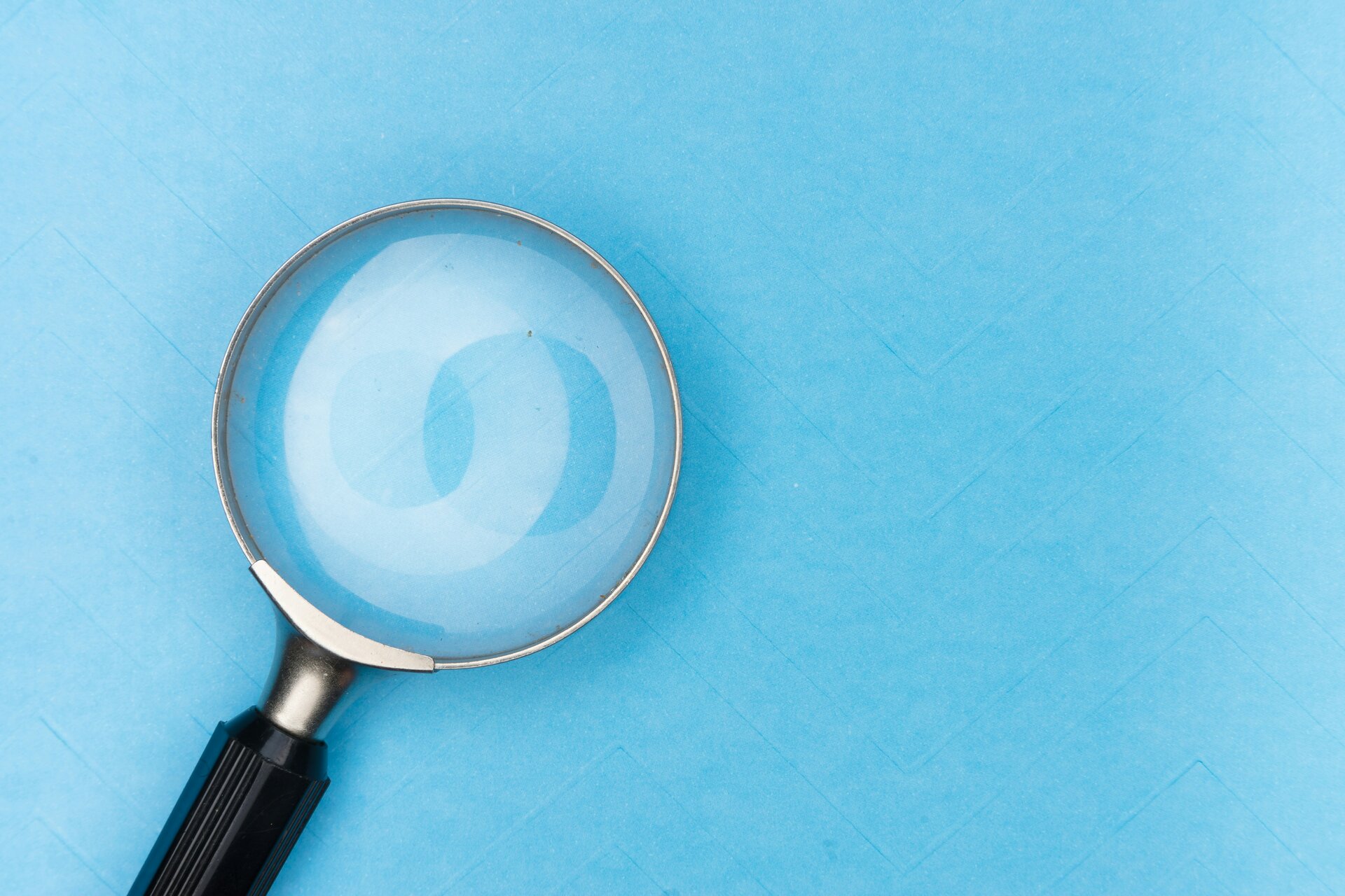 Auslandsreisekrankenversicherung: Auf diese Kriterien sollten Sie achten | © Markus Winkler/Unsplash Das Bild zeigt eine Lupe vor einem blauen Hintergrund | © Markus Winkler/Unsplash