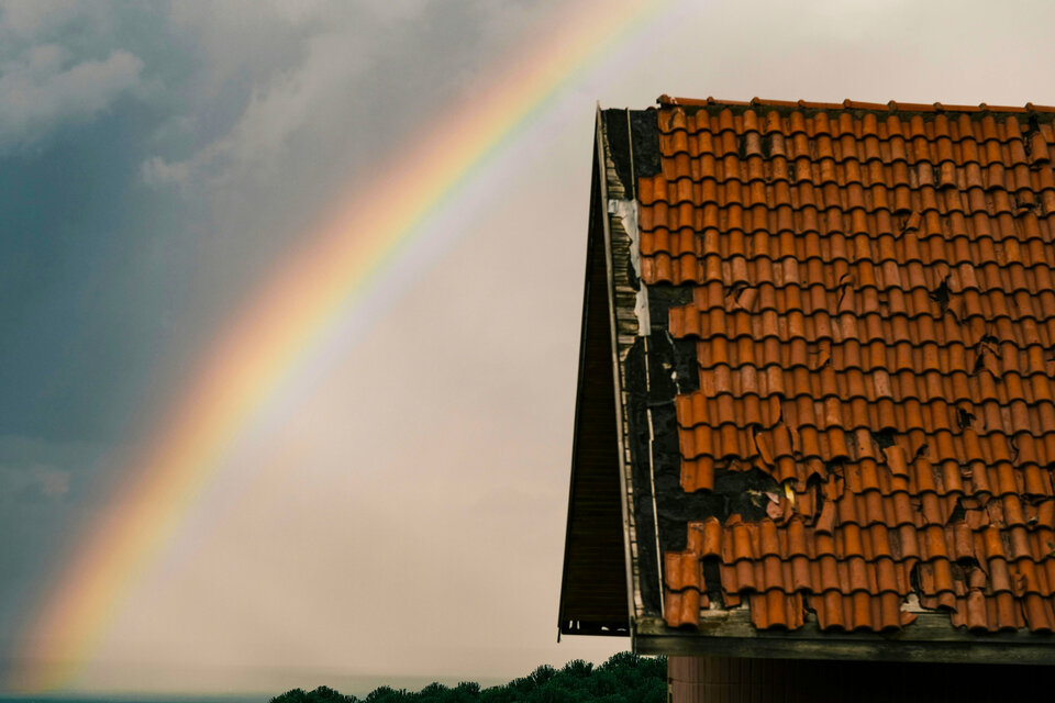 Sturmschäden: Welche Versicherung zahlt für welchen Schaden? | © Sami Aksu / Pexels Ein Regenbogen erstreckt sich über ein vom Sturm geschädigtes Hausdach. | © Sami Aksu / Pexels